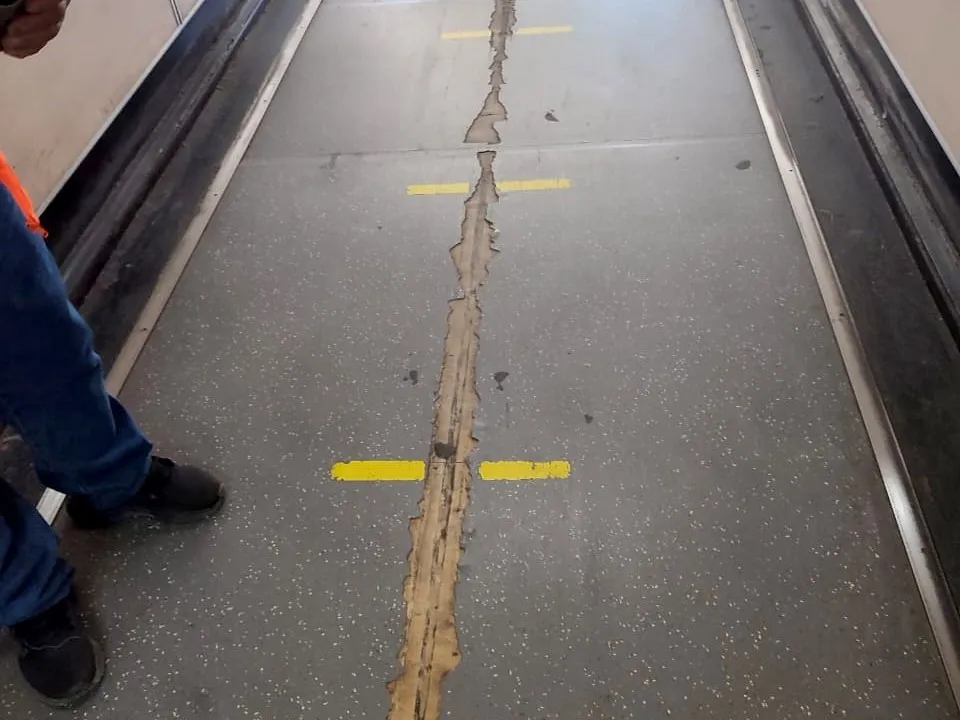 Piso interior de una pasarela de embarque con la junta central deteriorada