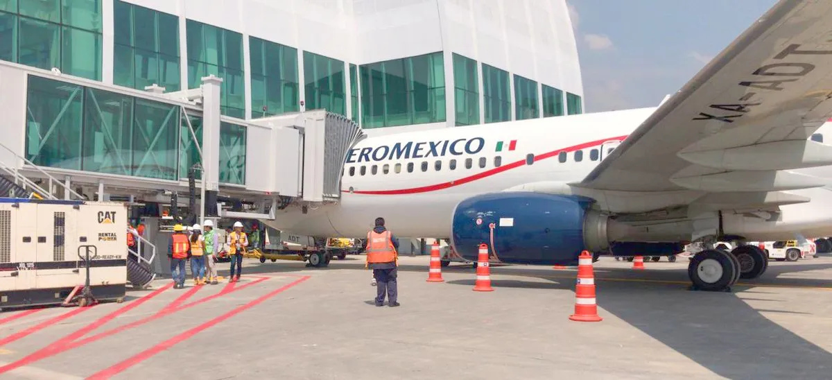 Pasarela de embarque de pasajeros y aeronave de Aeroméxico en la plataforma de un aeropuerto de México